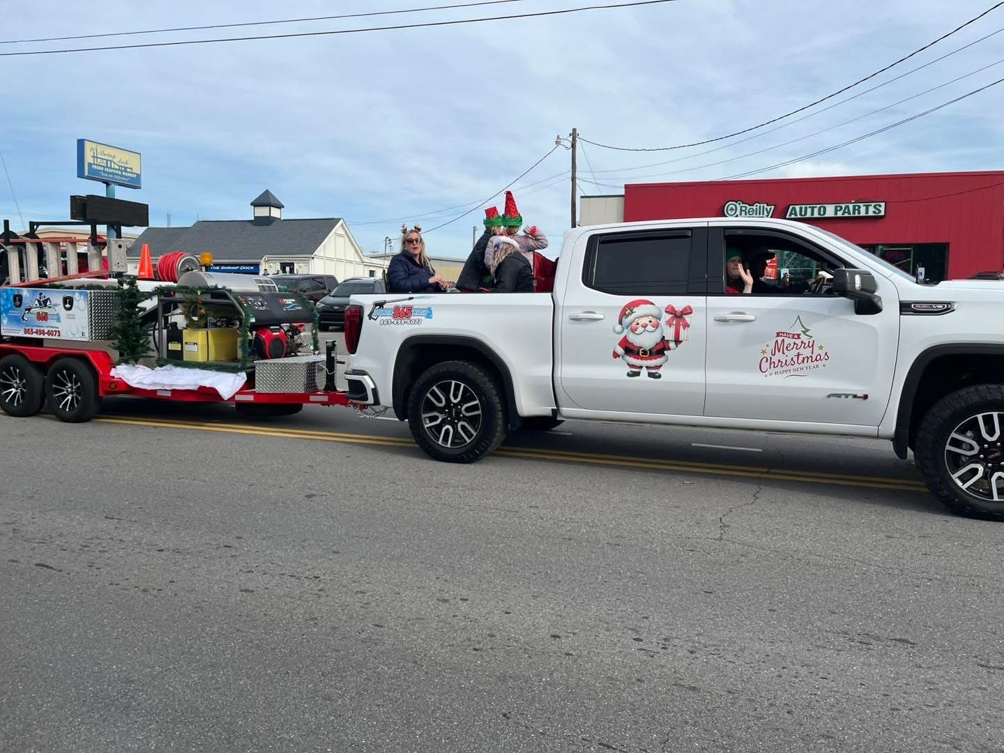A white truck with santa claus on the side is pulling a trailer.