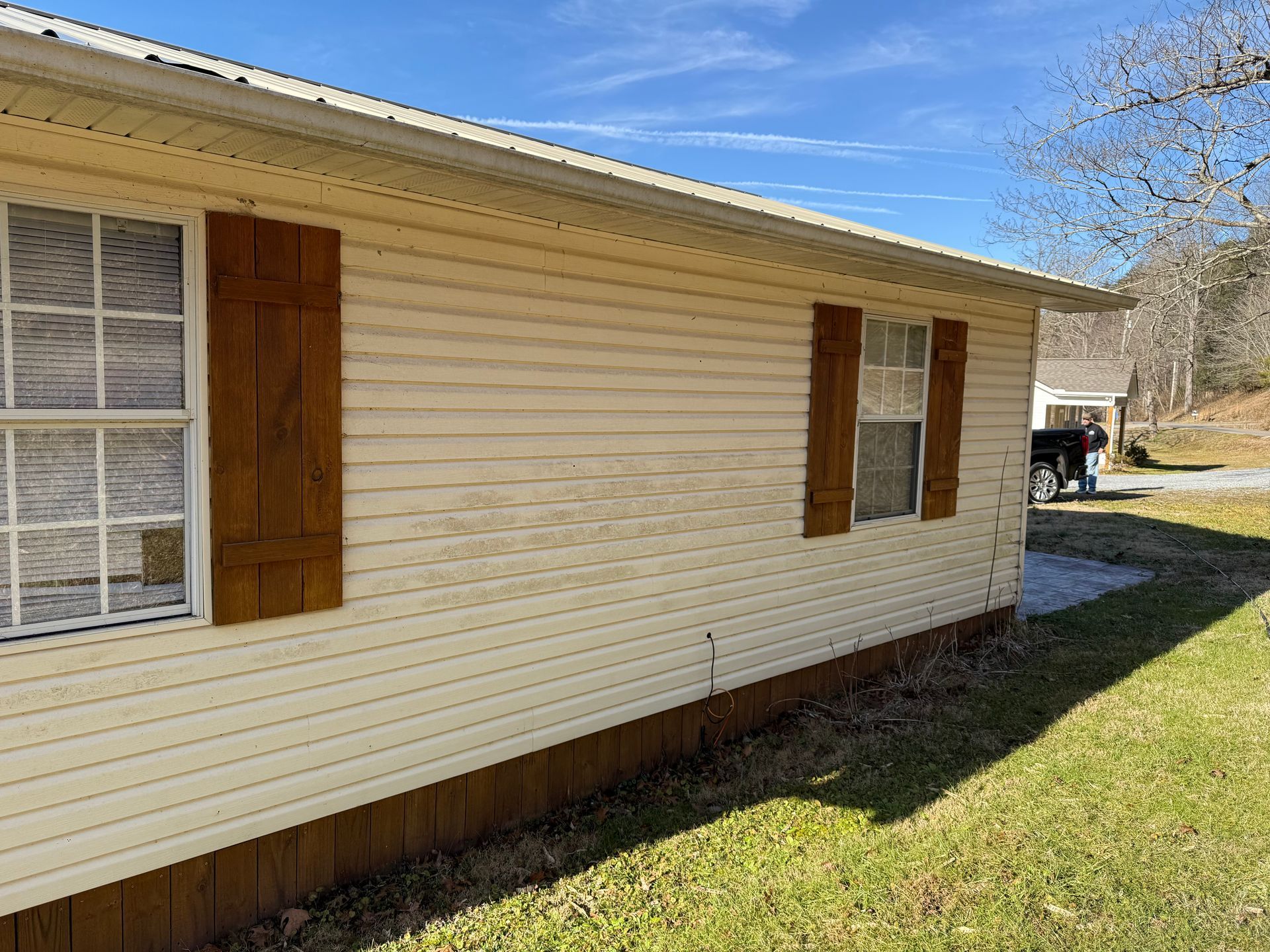 A white house with brown shutters on the windows and a truck parked in front of it.Job done by 865 Power Wash