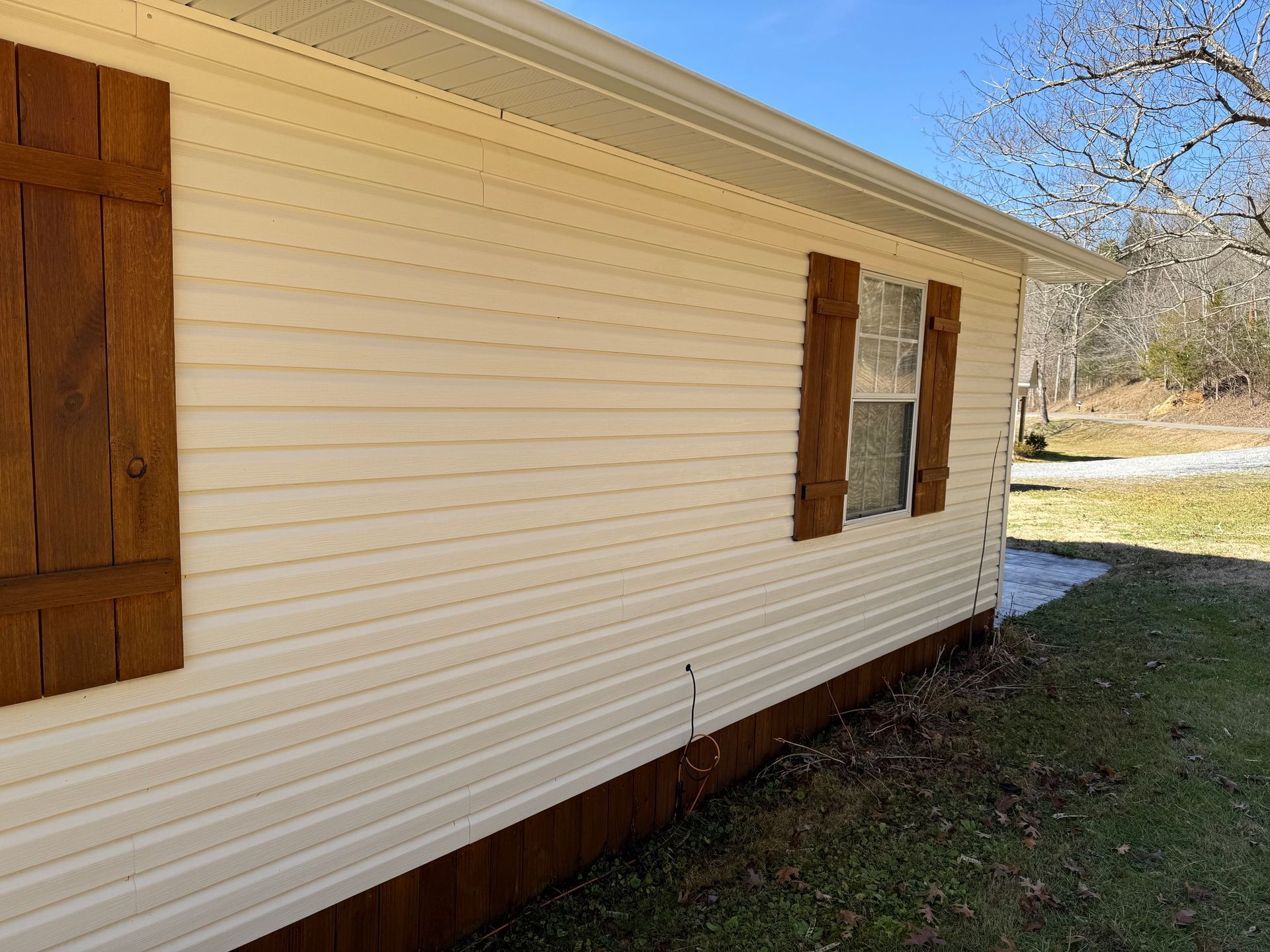 A white house with brown shutters on the windows. Job done by 865 Power Wash