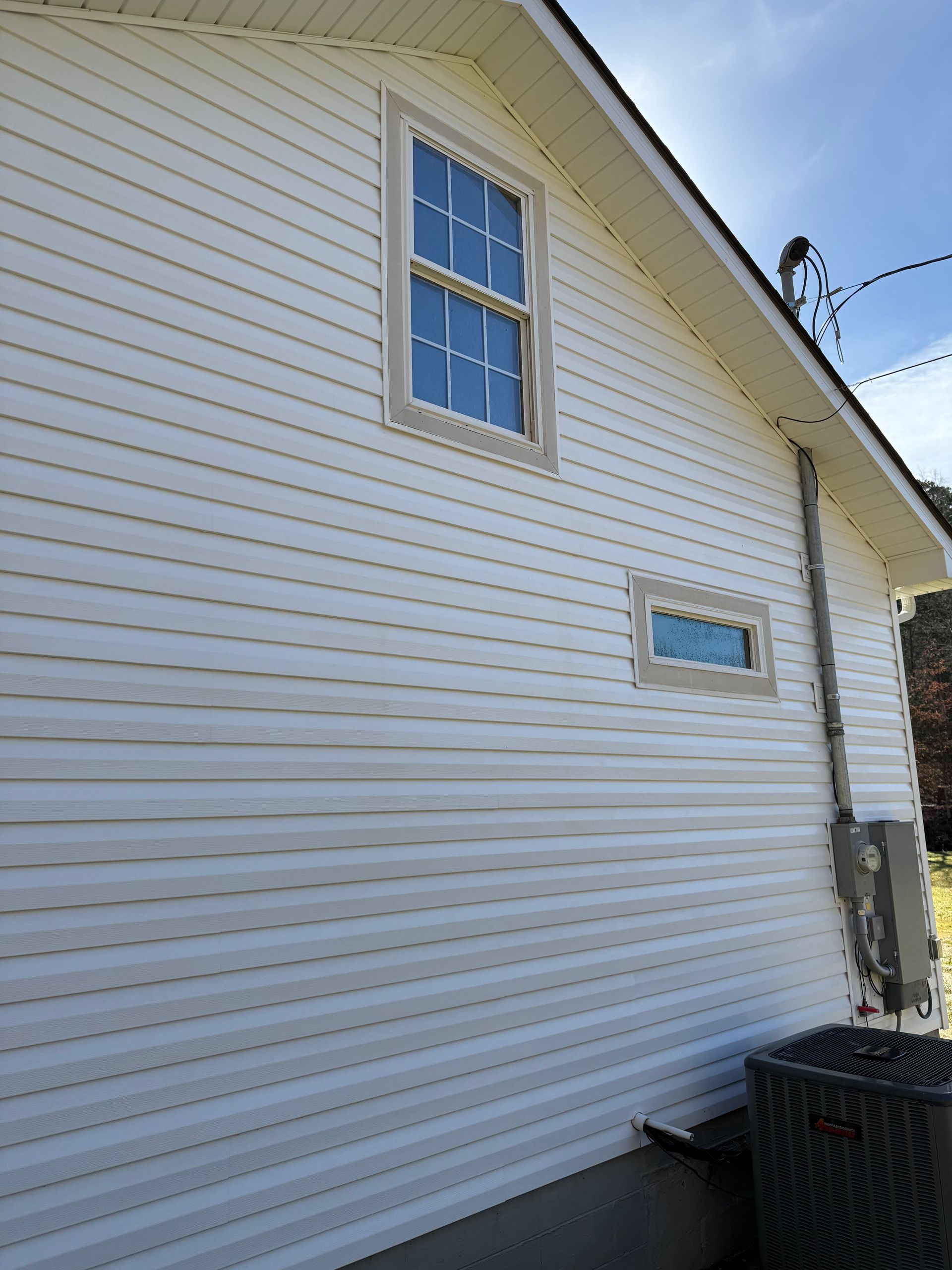 A white house with a window on the side Job done by 865 Power Wash