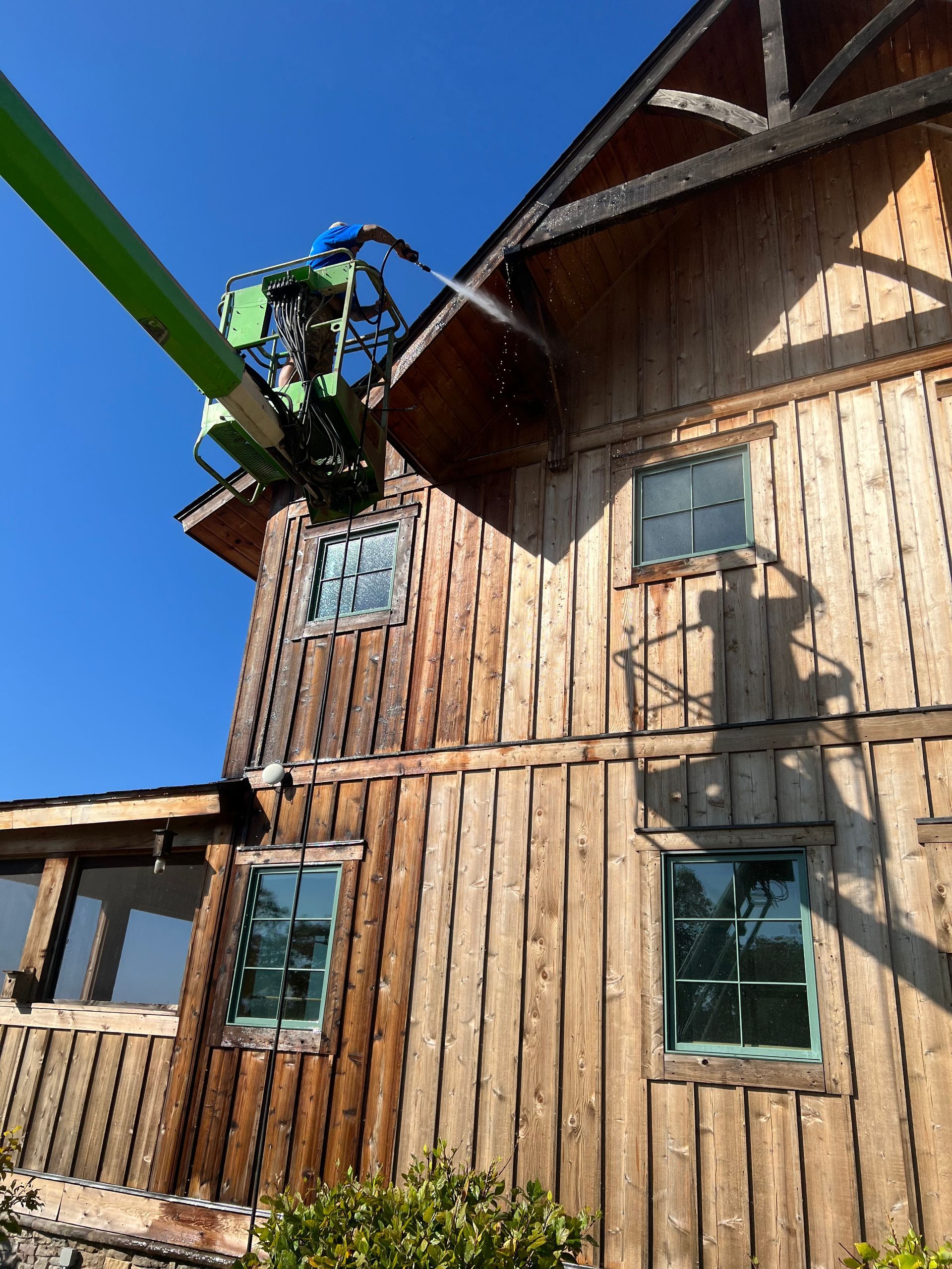 A green crane is spraying water on a wooden building