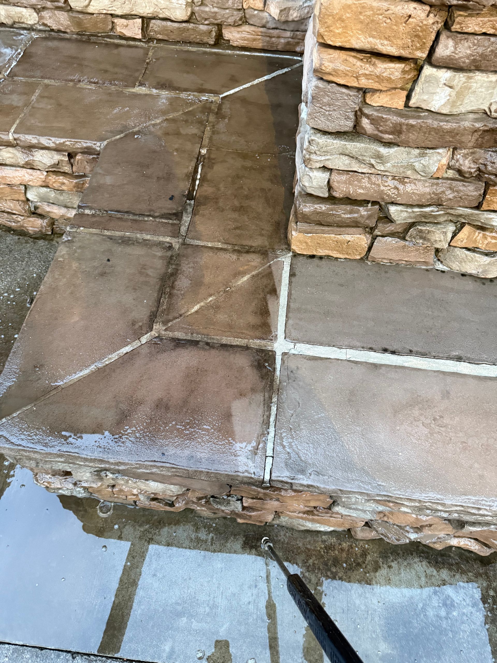 Power washing stone patio and rock wall.