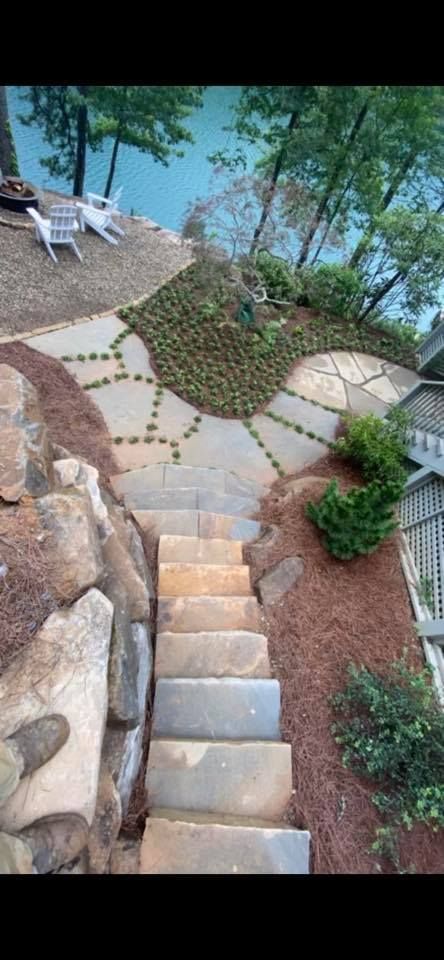 Stone steps winding through a landscaped garden beside a pool and patio with lounge chairs