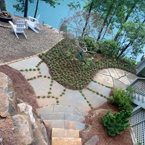 A straight, newly installed gravel garden path bordered by black landscape edging, flanked by lawn and scattered stones.