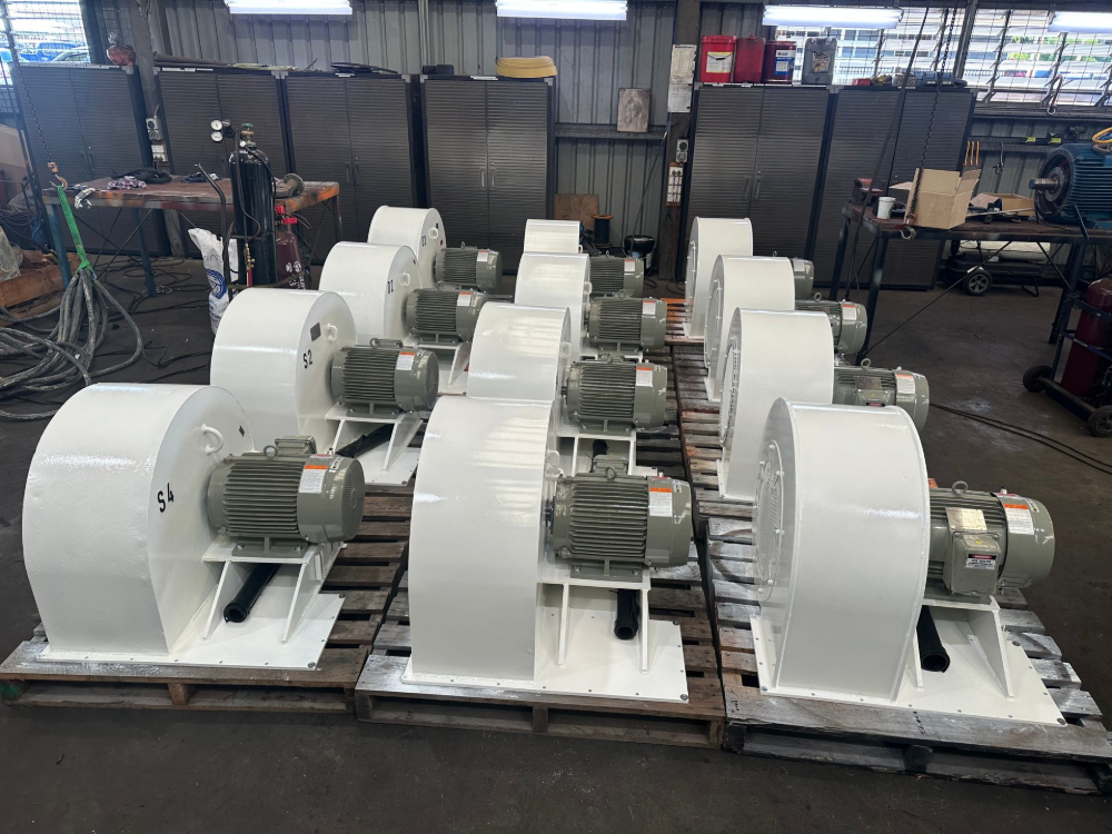 Several white industrial blowers on wooden pallets in a factory setting.— Davidson's Electrical In Parkhurst, QLD