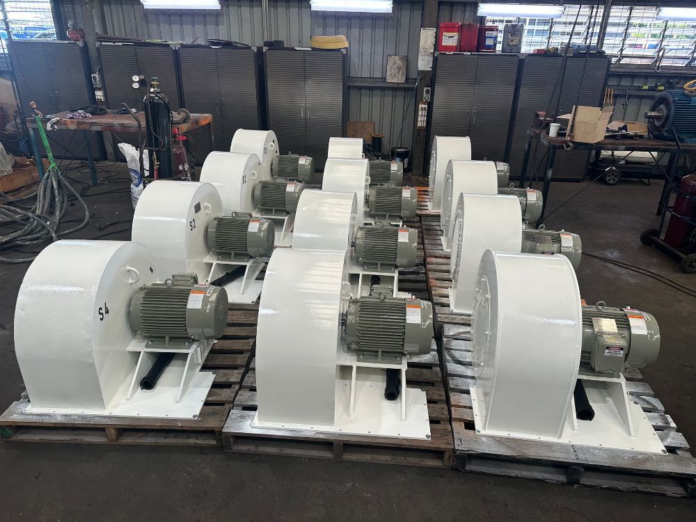 A bunch of white fans sitting on top of wooden pallets in a factory — Davidson's Electrical In Parkhurst, QLD