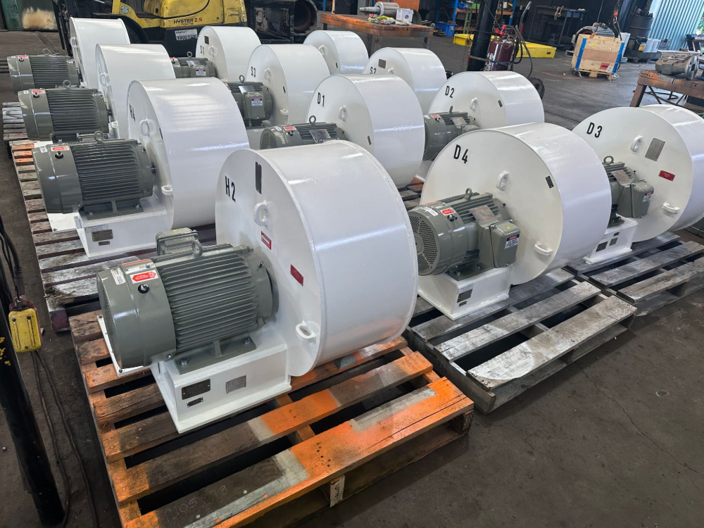 Several white industrial fans with motors on pallets in a warehouse.— Davidson's Electrical In Parkhurst, QLD