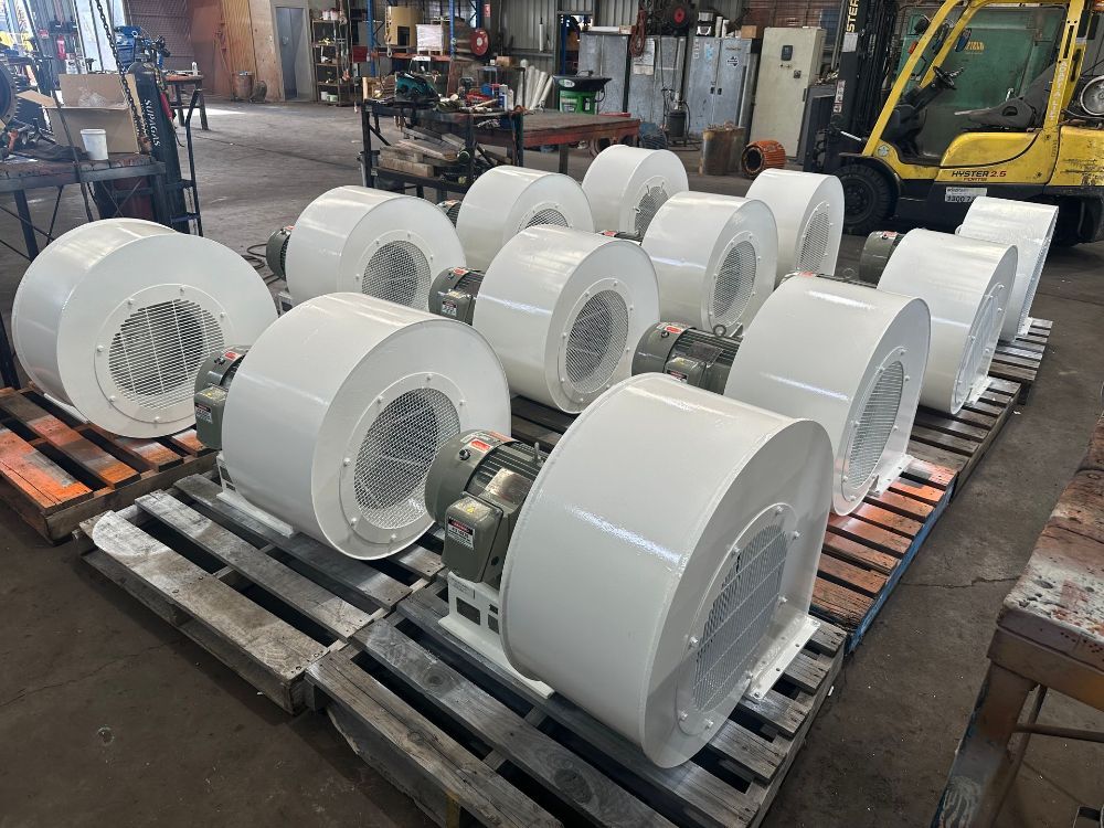 A bunch of white fans are sitting on a wooden pallet in a factory — Davidson's Electrical In Parkhurst, QLD