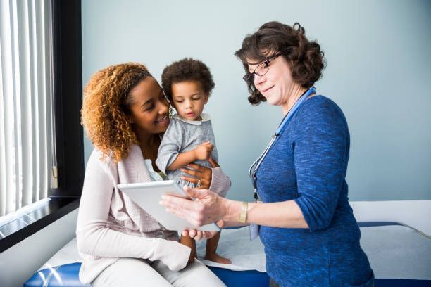 A woman is holding a child while talking to a doctor.