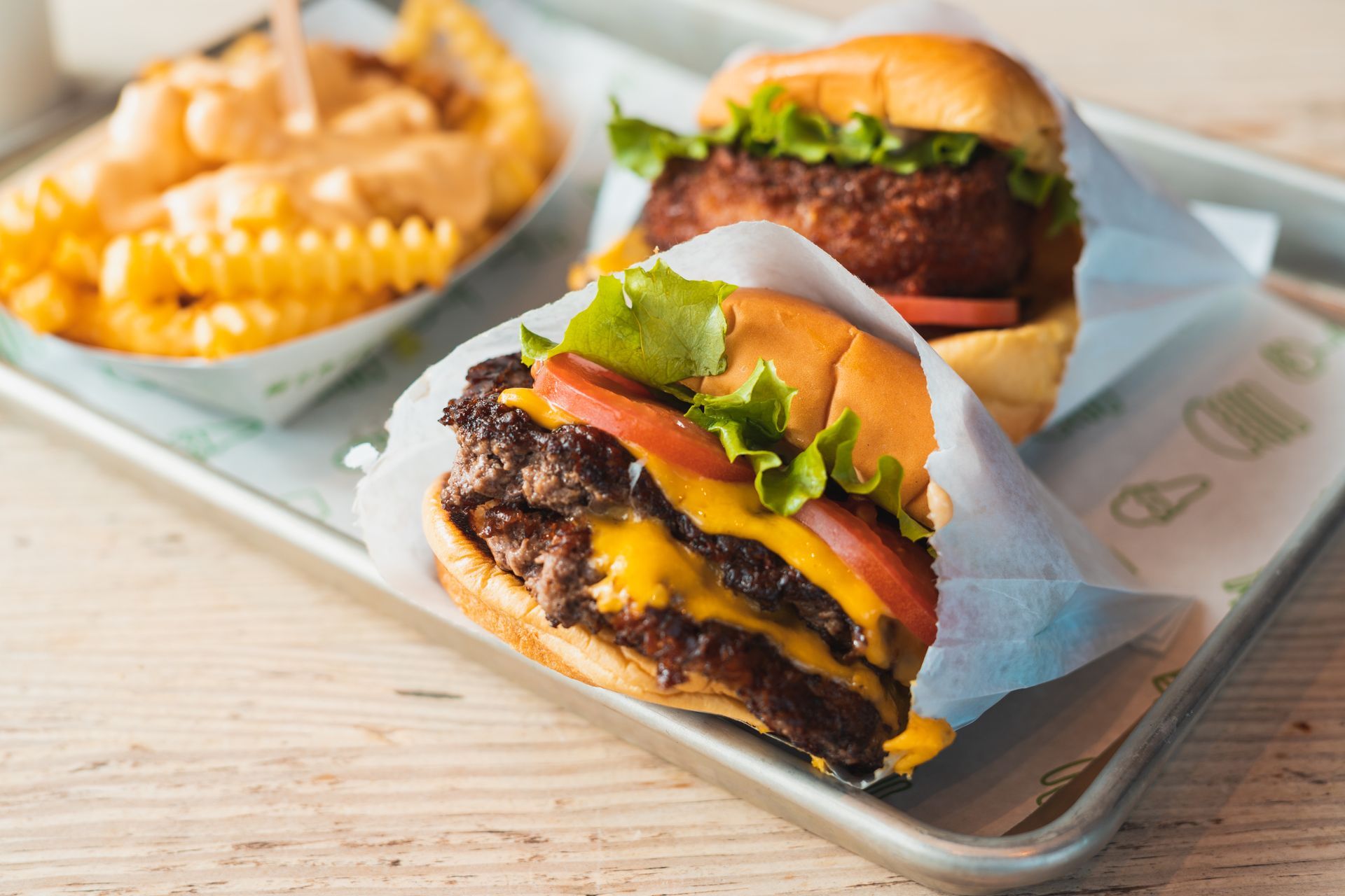 Two hamburgers and french fries on a tray on a table.