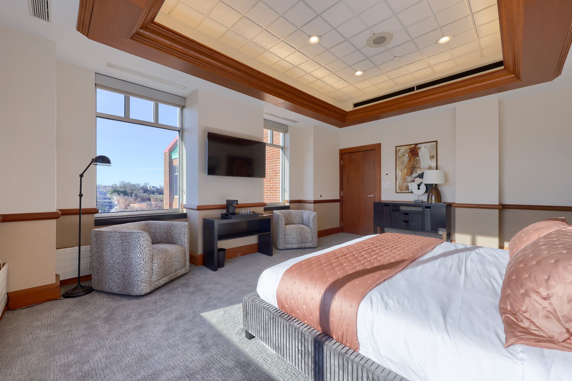 A hotel room with a bed , chairs , desk and television.