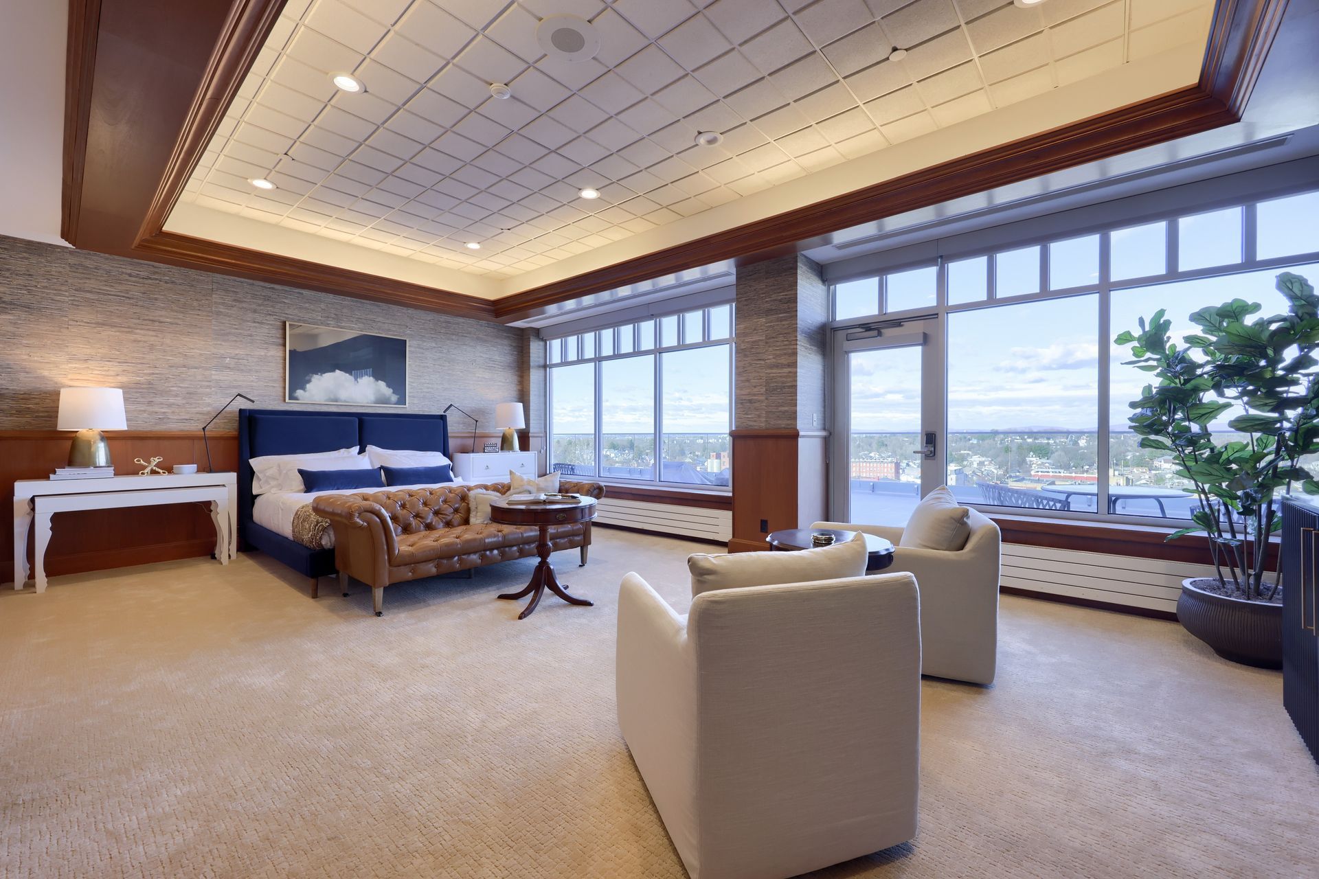 A large room with a bed , chairs , and a large window.