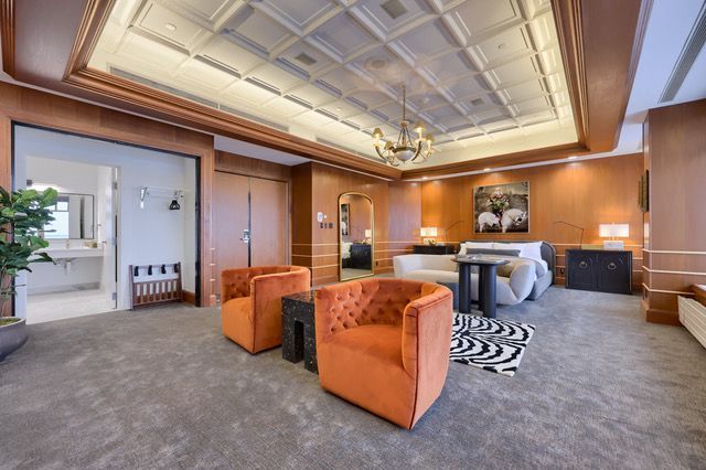 A hotel room with two orange chairs and a bed
