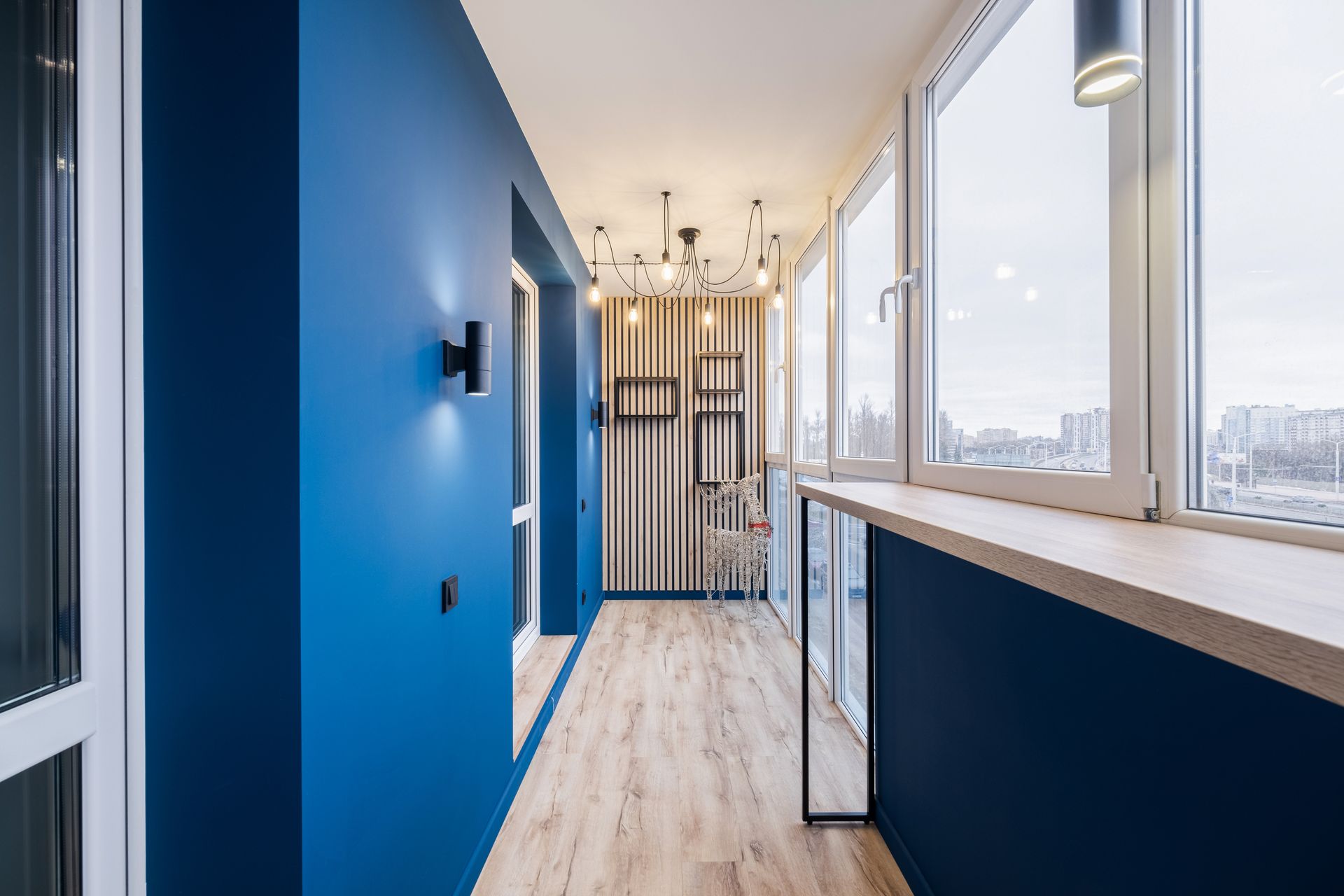 Bright blue hallway with wood floors, large windows, and glass doors in a modern building Bright blue hallway with wood floors, large windows, and glass doors in a modern building