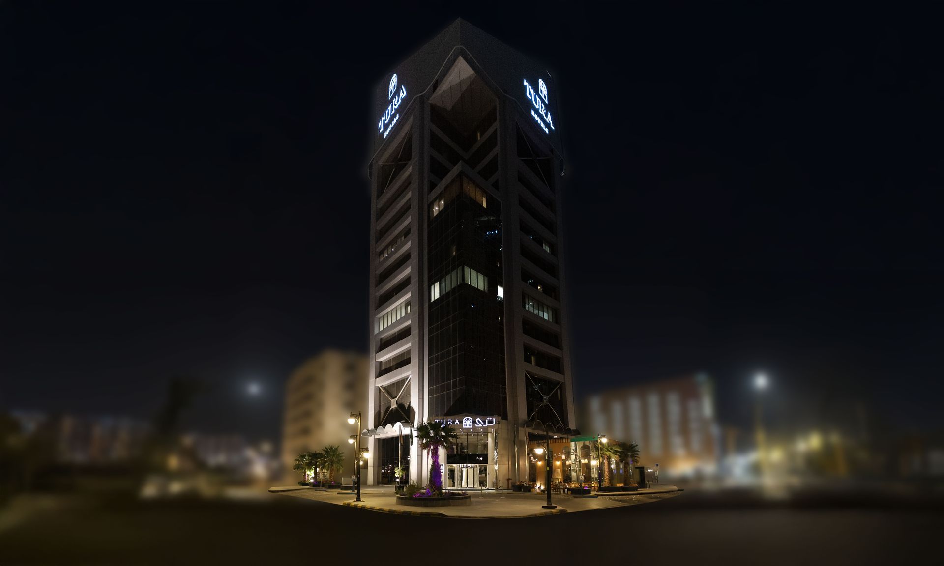 Nighttime view of a tall illuminated office tower on a city street corner