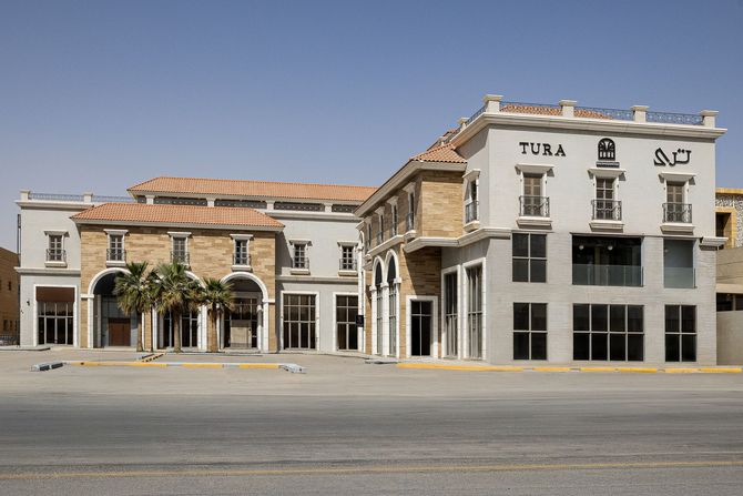 A multi-story building with tan stone and grey sections, featuring arched entrances and a 