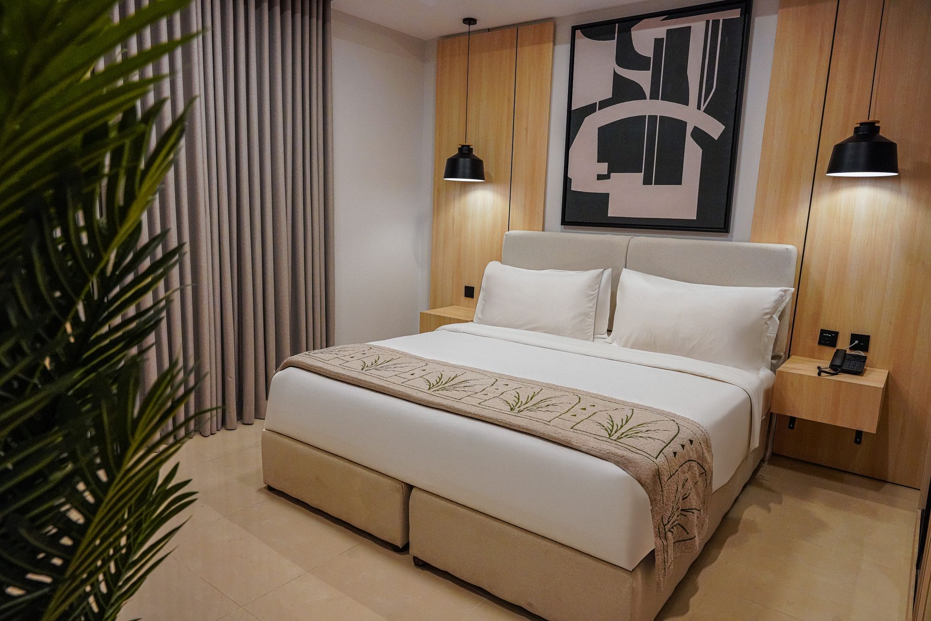 Modern bedroom with a neatly made bed, warm wood nightstands, wall art, and soft bedside lighting