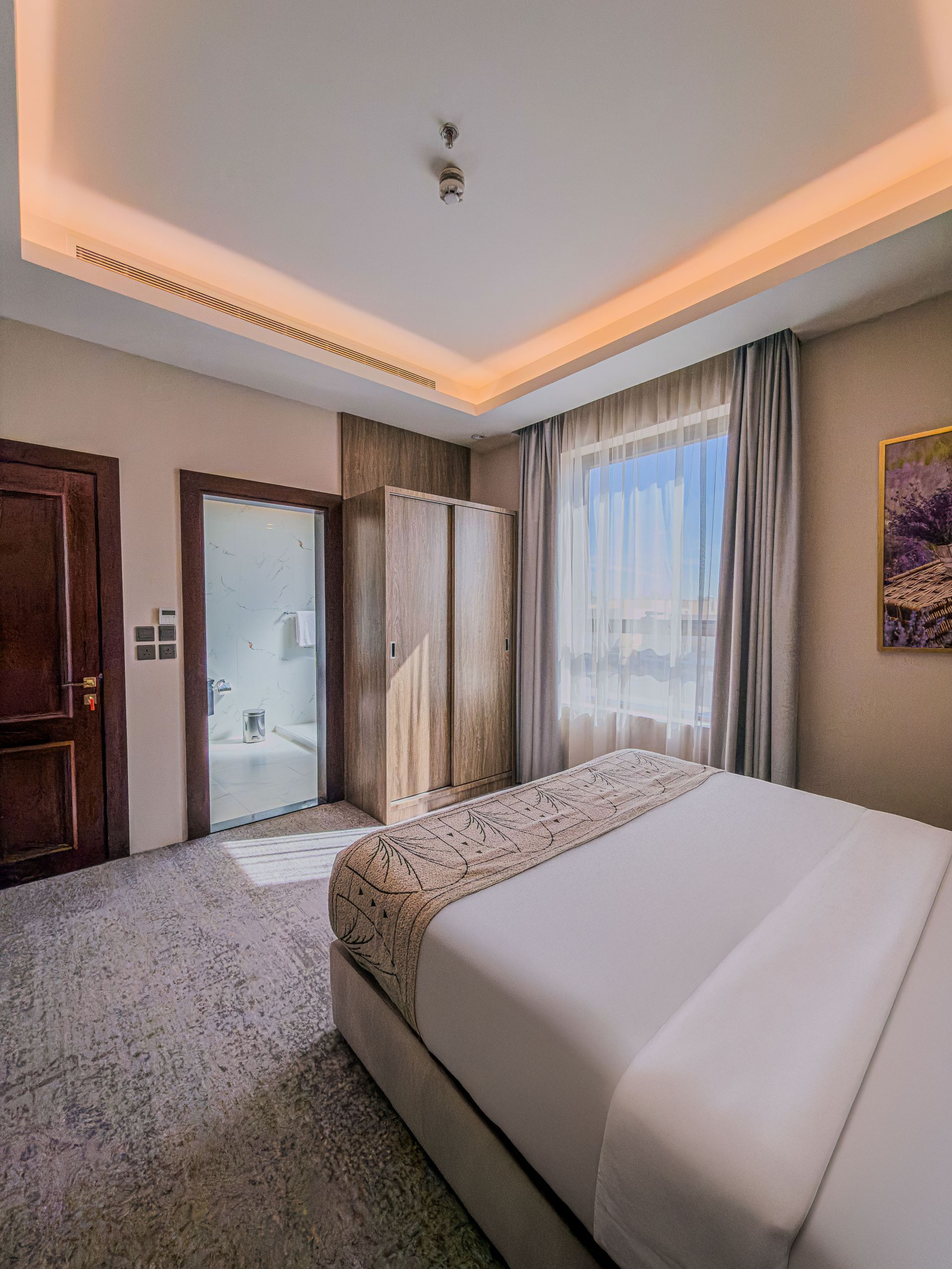 Modern bedroom with a bed, wooden wardrobe, large window, and warm ceiling lighting