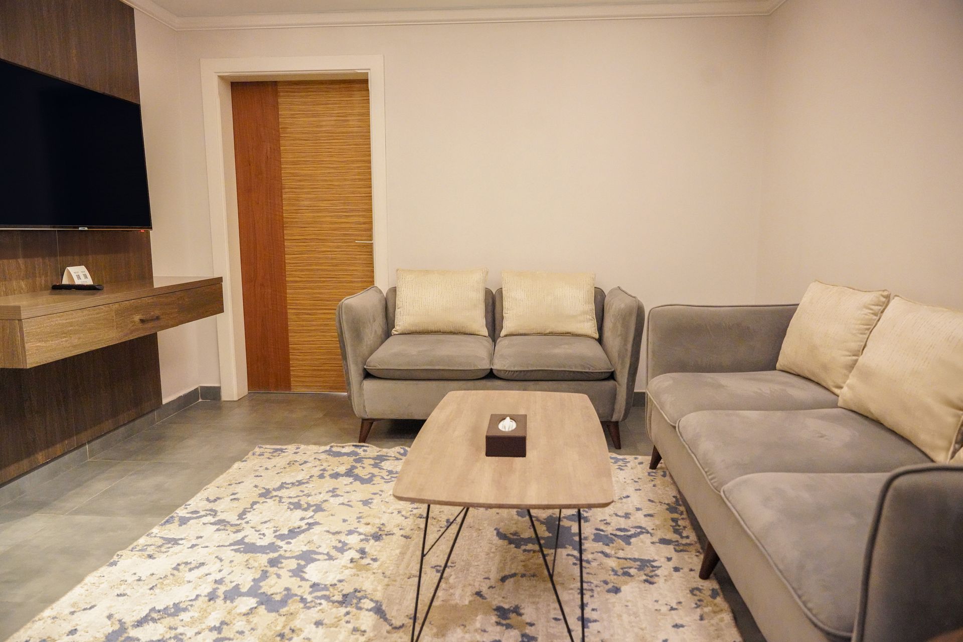 Modern living room with gray sectional, coffee table, fireplace, and patterned rug