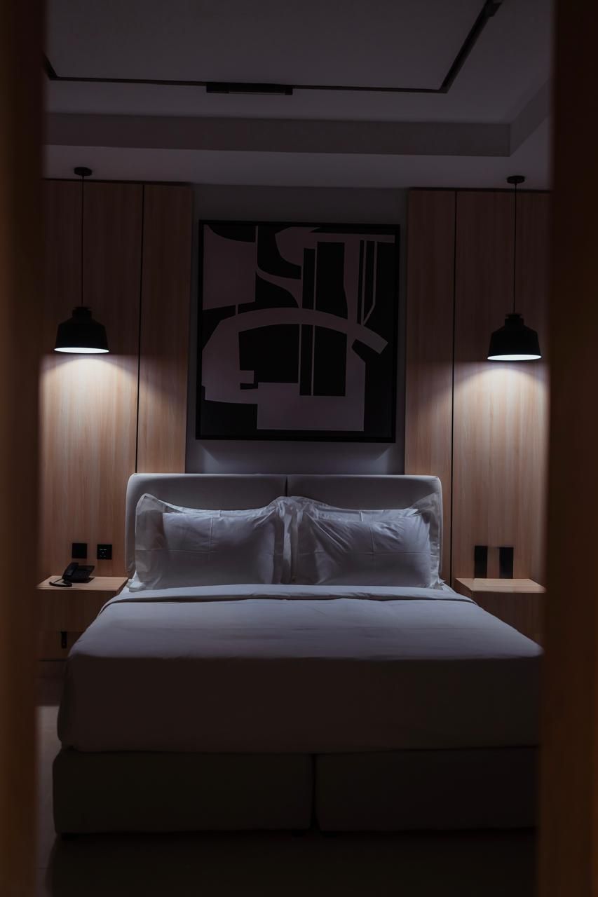 Modern bedroom with a neatly made bed, wall art, and two hanging bedside lamps