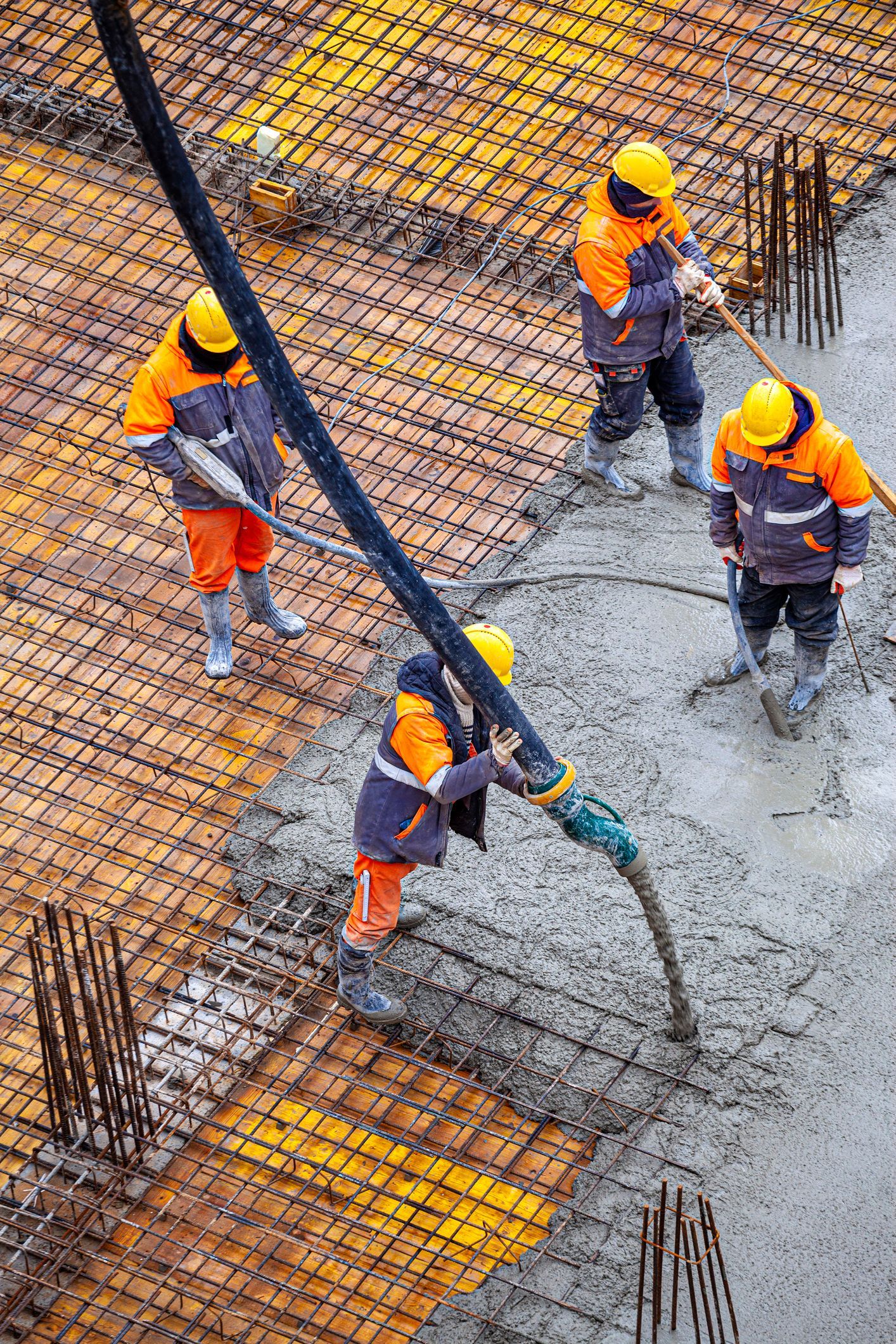 A group of construction workers are pouring concrete on a construction site.
