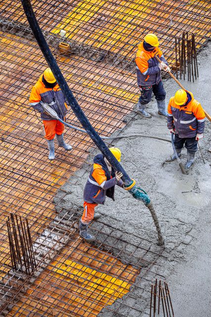 A group of construction workers are pouring concrete on a construction site.