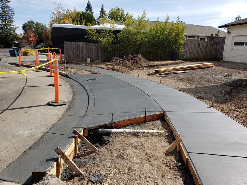 A concrete walkway is being built in front of a house