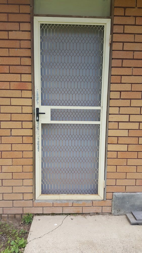 A White Screen Door is Sitting on a Brick Wall — Lismore Blinds in North Lismore, NSW