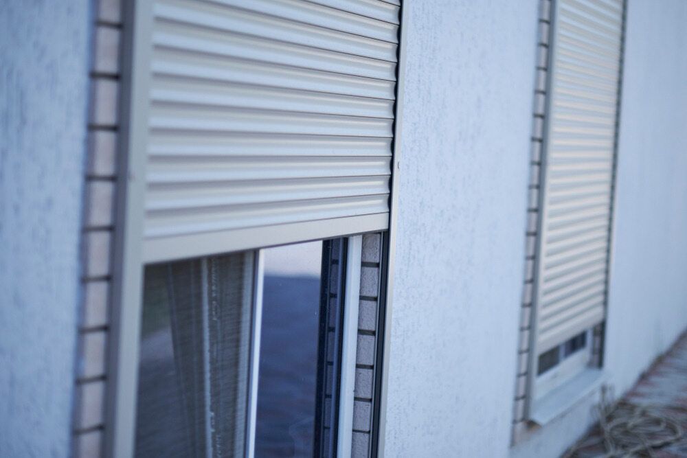 A White Building With Two Windows With Roller Shutters on Them — Lismore Blinds in Kyogle, NSW