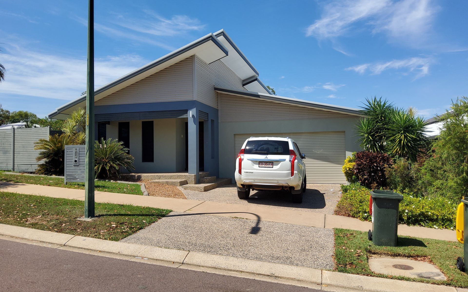 A Modern House With a White Car Parked in the Driveway on a Sunny Day — EXPOSURE NORTH PLASTERING PTY LTD in Berry Springs, NT