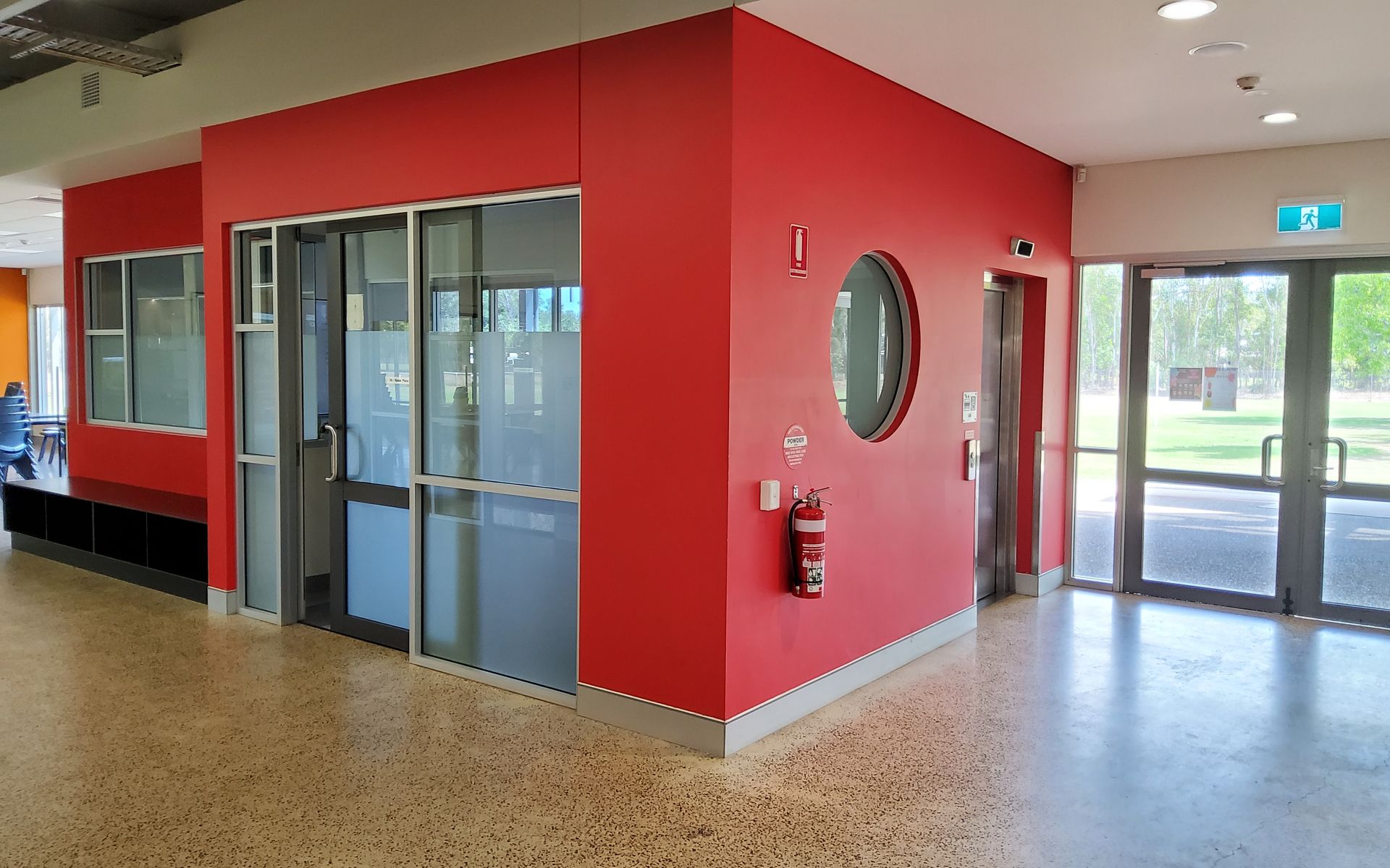 Red-walled Hallway With a Fire Extinguisher, a Round Window, and Glass Doors Leading Outside — EXPOSURE NORTH PLASTERING PTY LTD in Berry Springs, NT