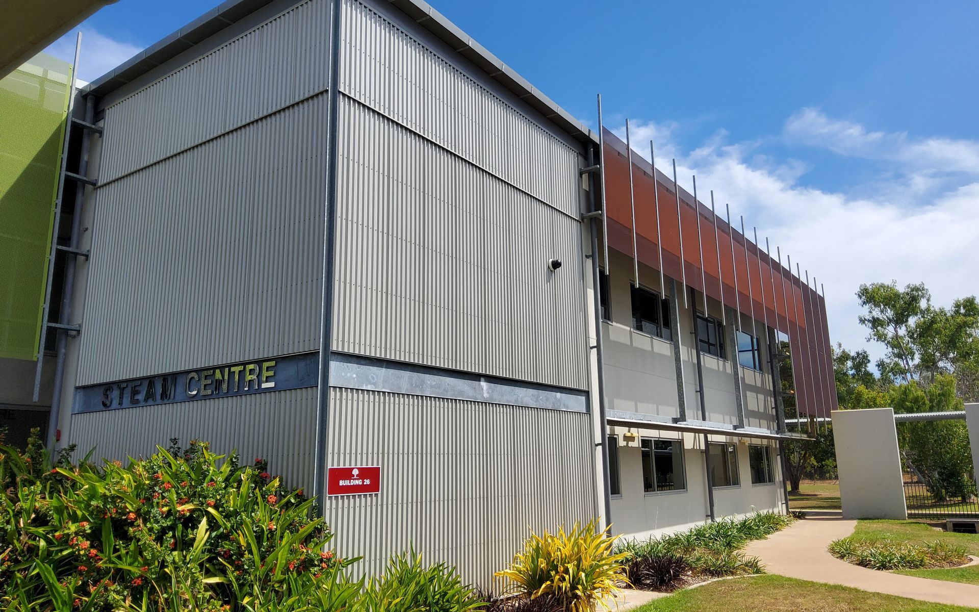 STEAM Centre Building With Corrugated Silver Siding, Brown Screening, and Greenery Against a Blue Sky — EXPOSURE NORTH PLASTERING PTY LTD in Berry Springs, NT