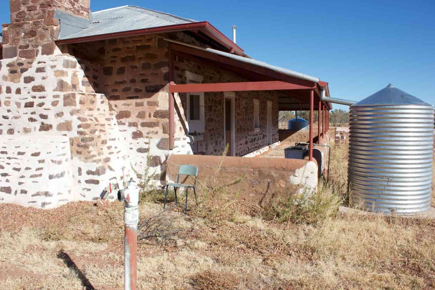 Stone House With a Red-roofed Porch and Metal Water Tank — EXPOSURE NORTH PLASTERING PTY LTD in Berry Springs, NT