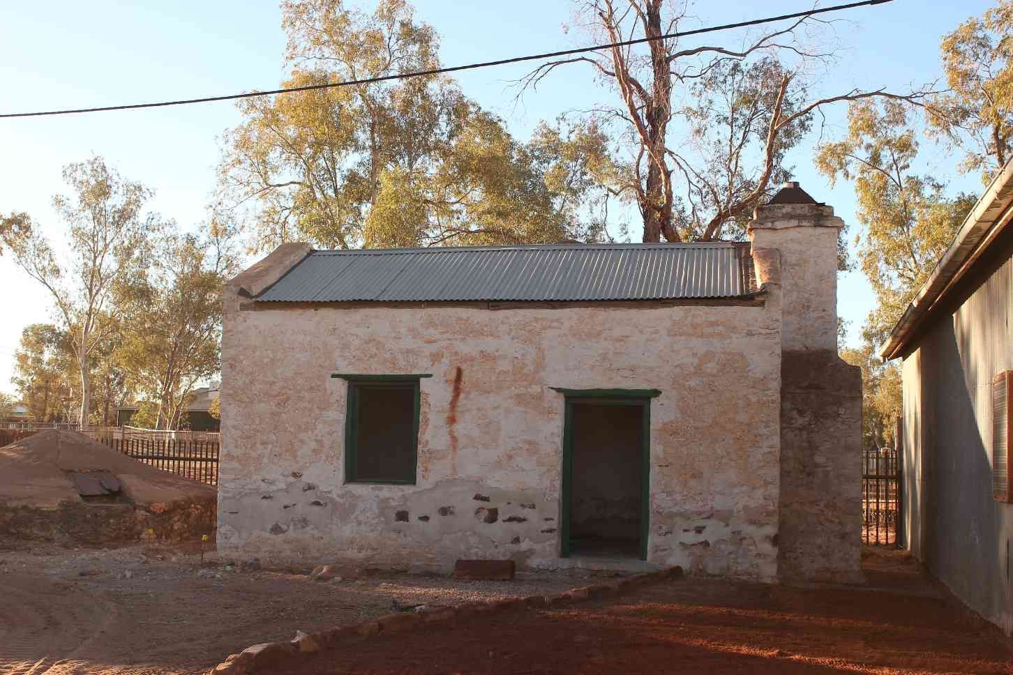 Old Weathered Stone Building with A Metal Roof, Green-Framed Windows, and A Brick Chimney — EXPOSURE NORTH PLASTERING PTY LTD in Berry Springs, NT