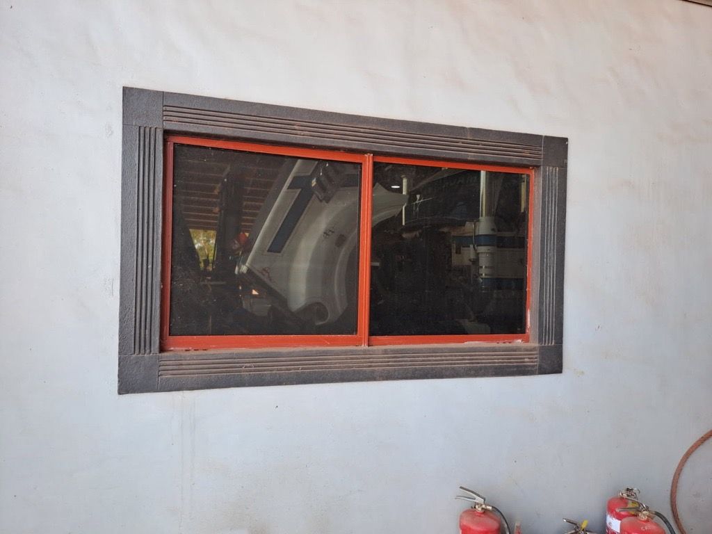Window in A Gray Wall, Red Frame, Dark Screen, and Ornate Dark Gray Trim — EXPOSURE NORTH PLASTERING PTY LTD in Berry Springs, NT