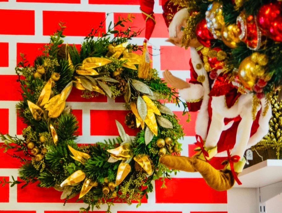 A christmas wreath is hanging on a red brick wall.
