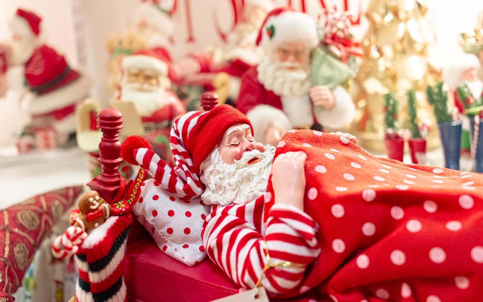 A figurine of santa claus is sleeping in a bed.