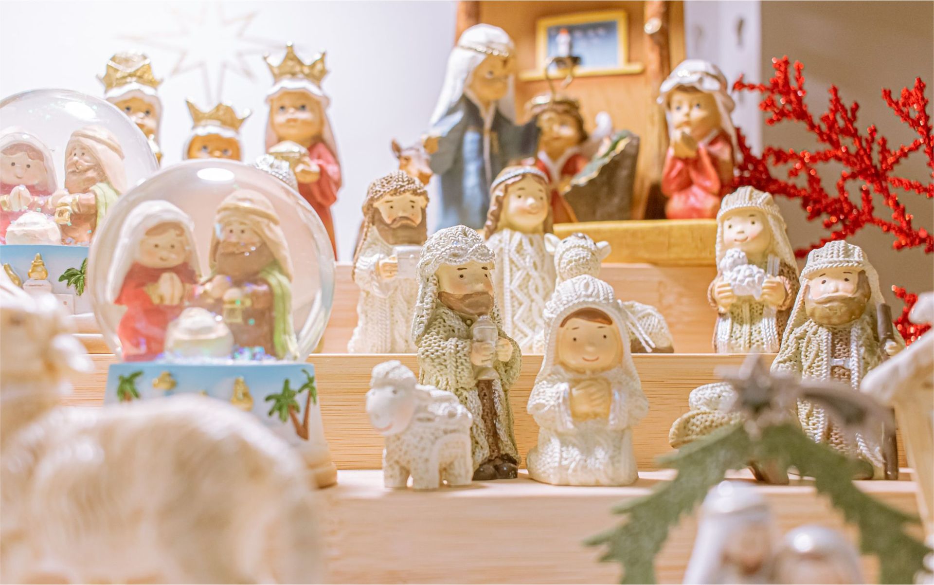 A nativity scene with snow globes and figurines on a wooden table.