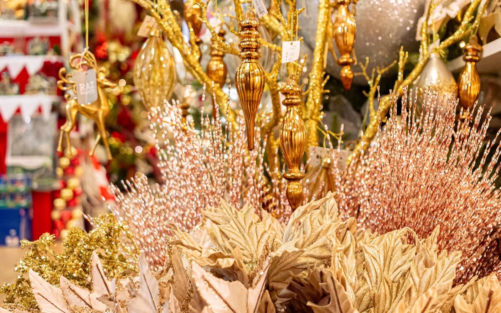 A bunch of christmas decorations are sitting on a table in front of a christmas tree.