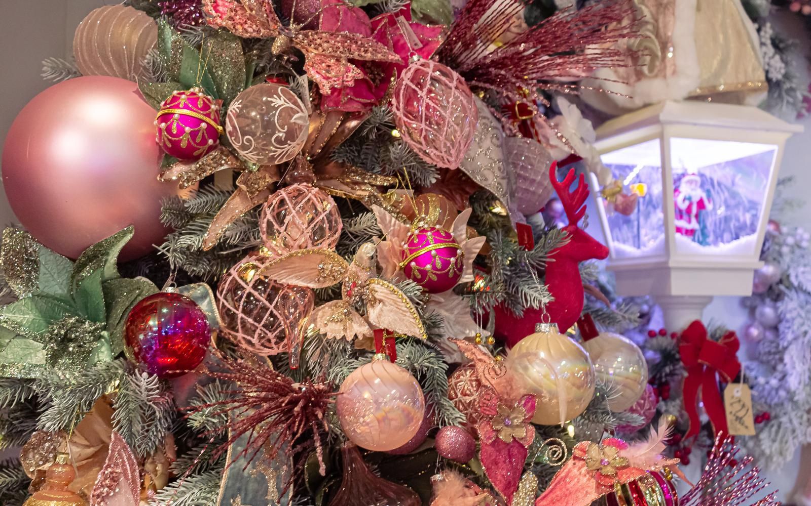 A close up of a christmas tree decorated with pink and gold decorations.
