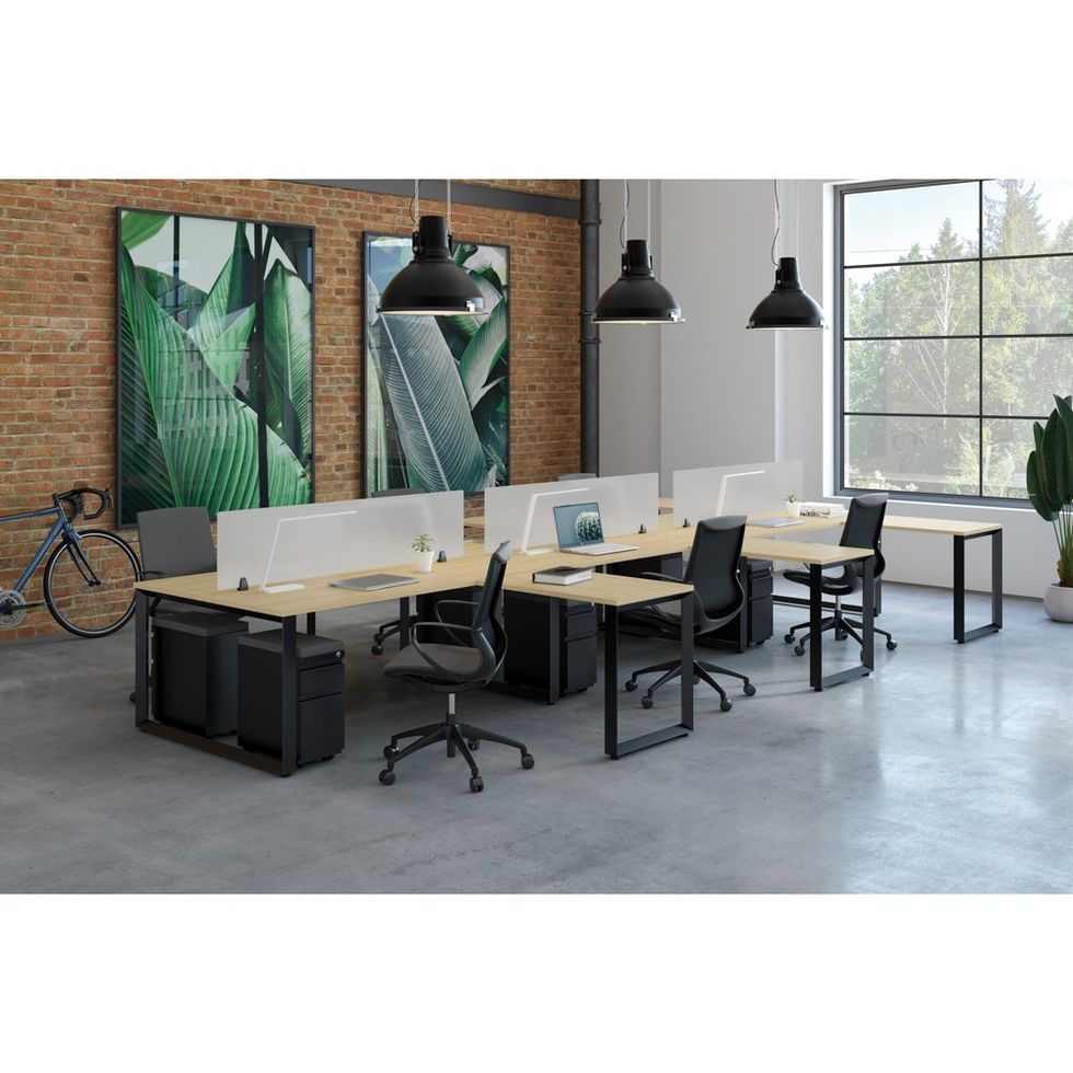 Modern open office with desks, chairs, hanging lamps, brick wall art, and large windows