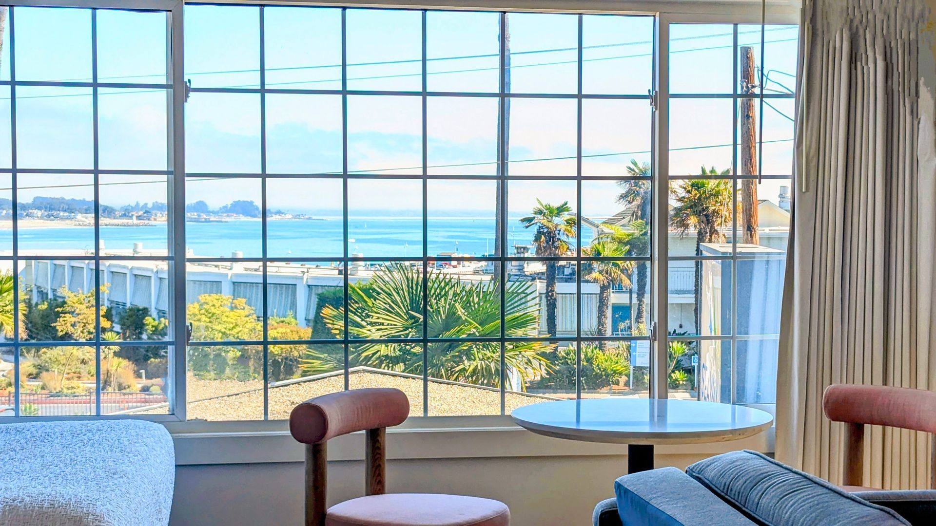 View of the ocean seen through a window behind a table with two chairs.
