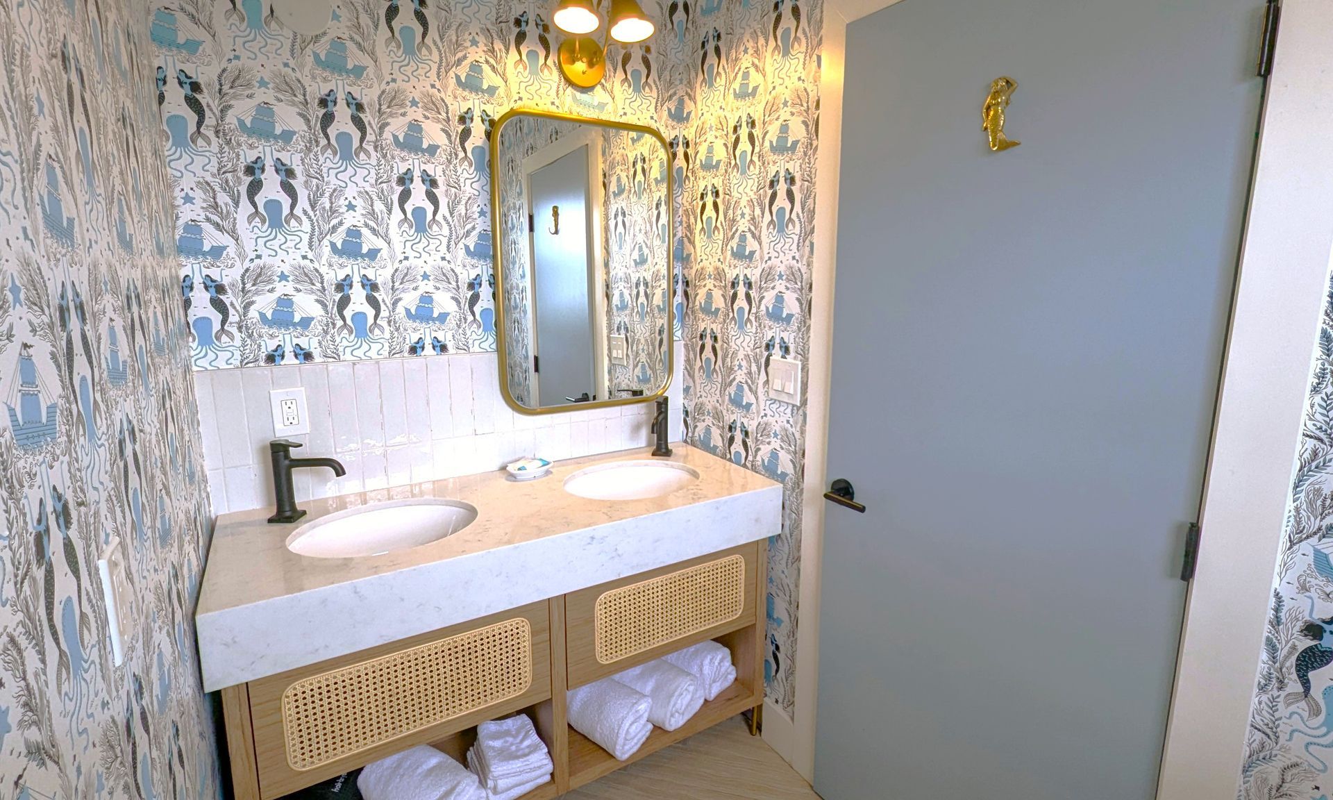 Bathroom counter with two sinks and towels on a shelf underneath