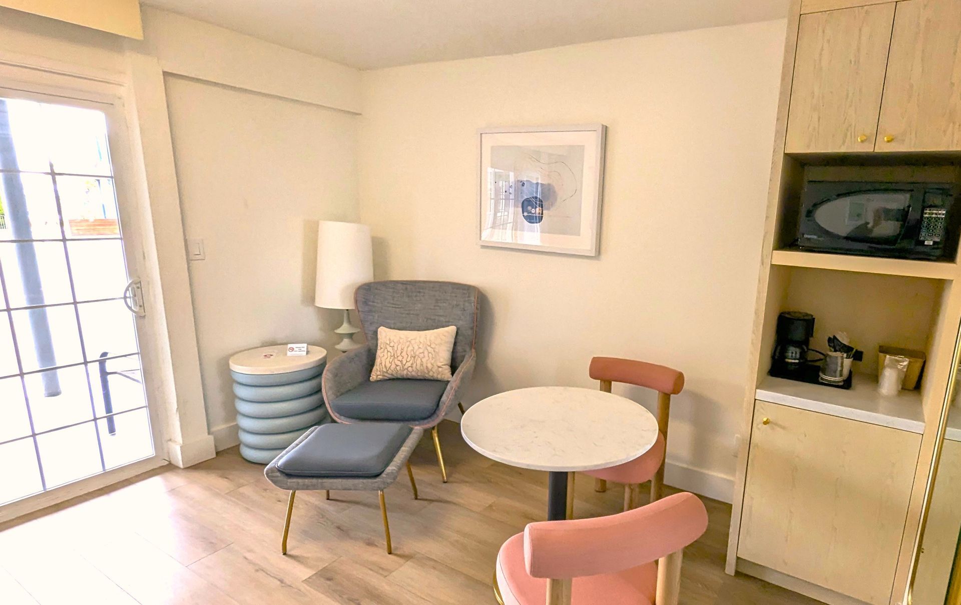 Blue/grey chair between floor lamp and a table with two fabric chairs
