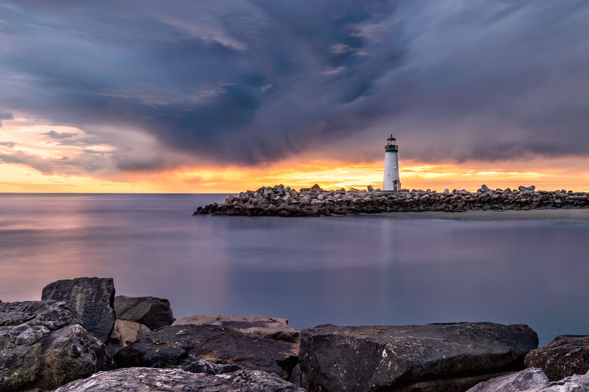A lighthouse across a small bay at sunset.