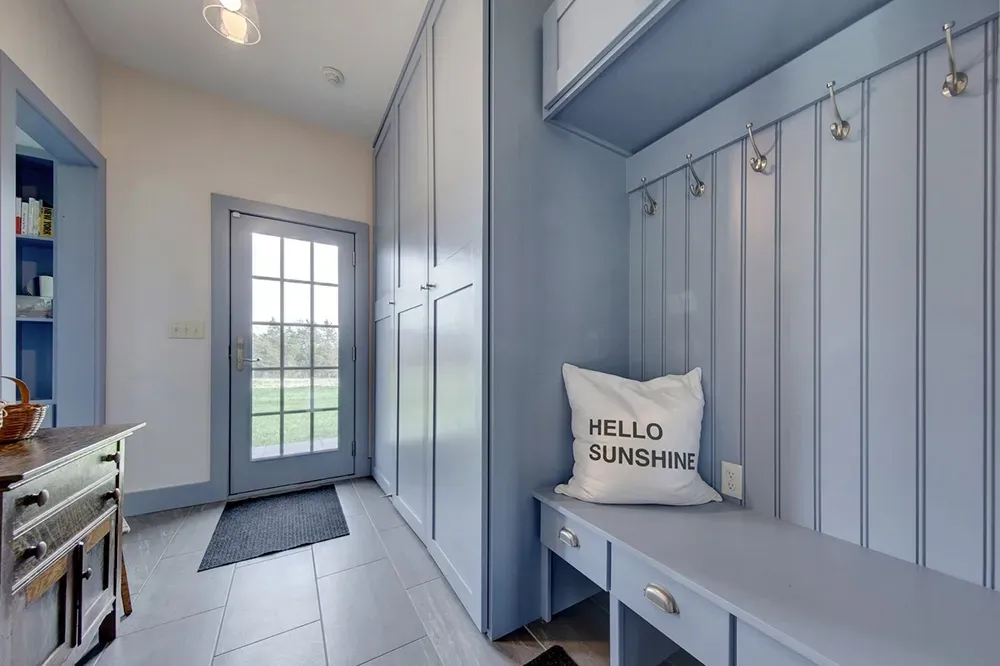 A mudroom with light blue built-in storage, a bench with a