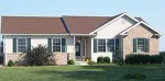 A one-story suburban home with beige siding, brick accents, a brown roof, and dark green shutters on a grassy lawn.