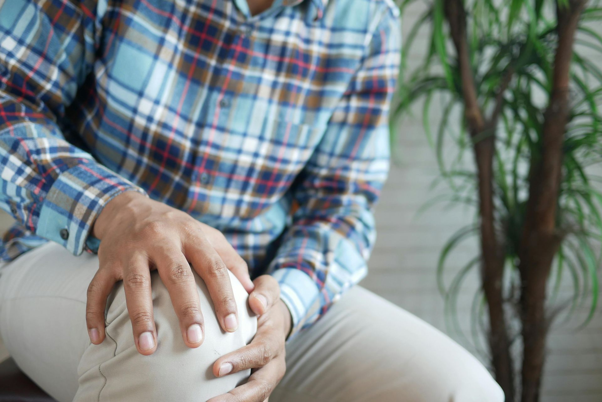 Person holding a swollen knee while seated indoors