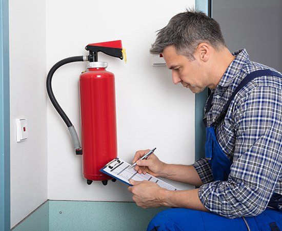 Man Inspecting Fire Extinguishers — Birmingham, AL — Automatic Fire Systems Man Inspecting Fire Extinguishers — Birmingham, AL — Automatic Fire Systems
