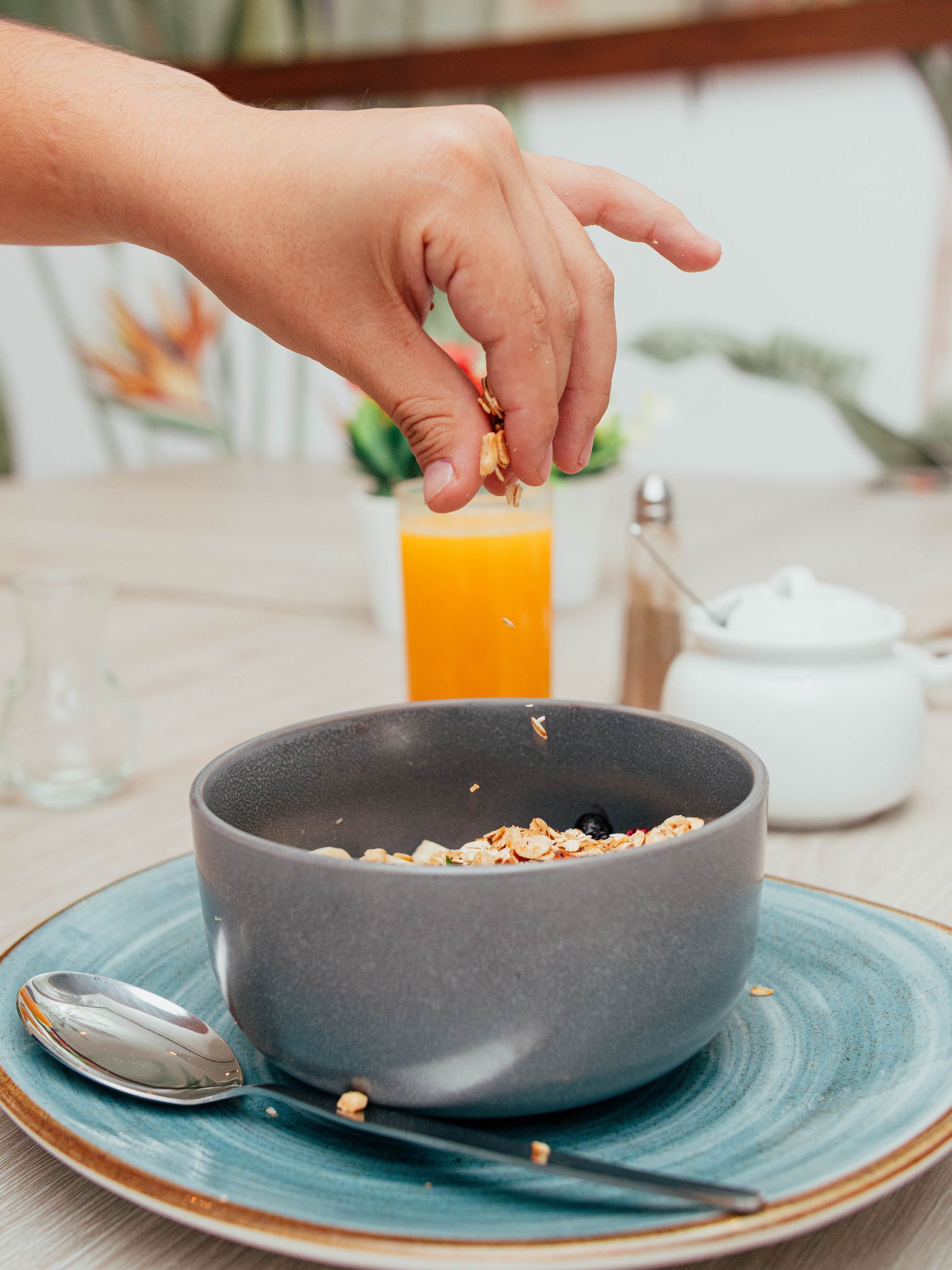 A person is putting nuts into a bowl of cereal.